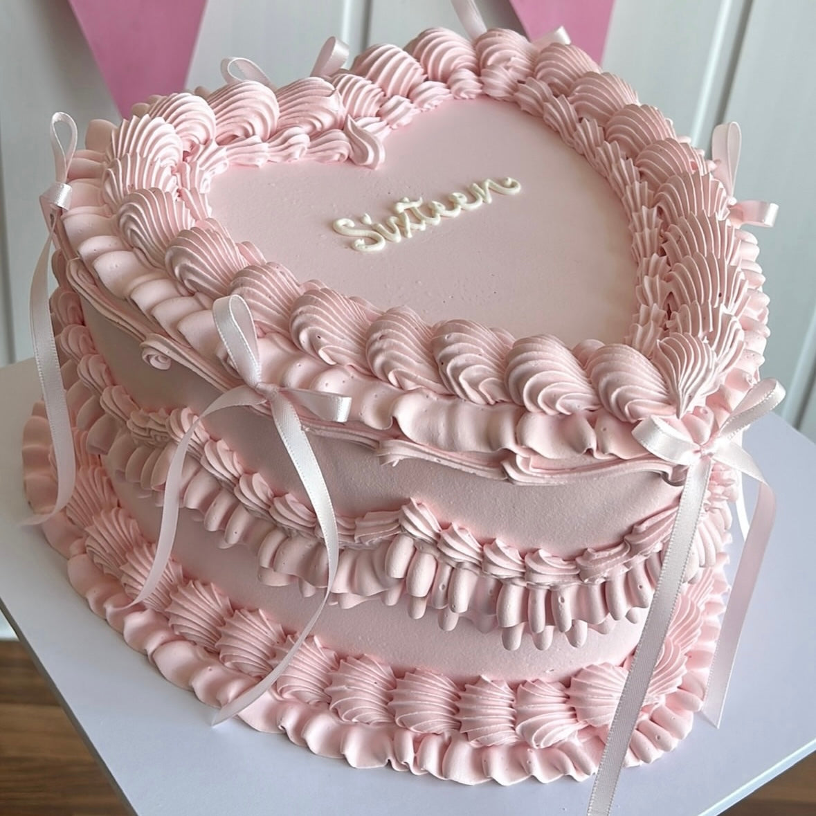 Vintage-inspired cake with layers of soft pink ruffles and satin bows, perfect for weddings, birthdays, or special celebrations.