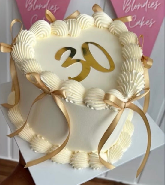 Cream coloured heart cake with border piping and satin bows 